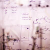 a close up of a whiteboard in a pharmacy lab with equations written on it